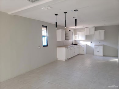 Kitchen featuring open shelves, white cabinetry, light countertops, light tile patterned floors, and hanging light fixtures