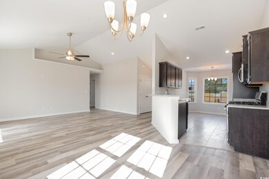 Kitchen featuring a chandelier, dark brown cabinetry, light countertops, open floor plan, and a ceiling fan