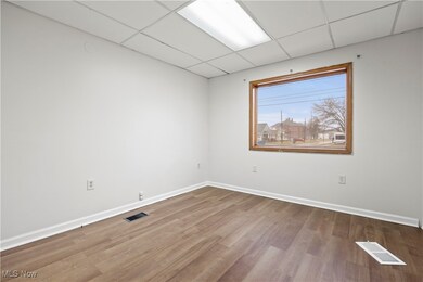 Empty room featuring a drop ceiling, baseboards, and wood finished floors