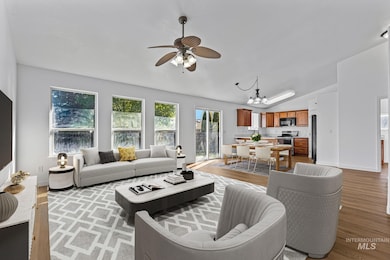 Living area with a ceiling fan, a chandelier, light wood-style floors, and vaulted ceiling