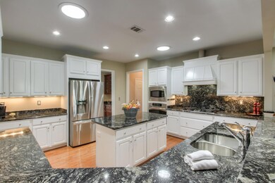Gourmet kitchen includes: white cabinetry, tempest black granite, hardwood, and stainless appliances.