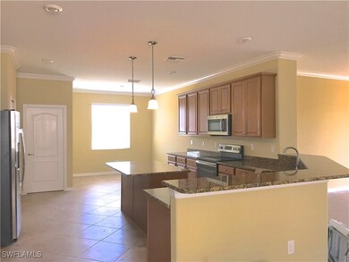 Kitchen with crown molding, stainless steel appliances, light tile patterned floors, a peninsula, and a center island