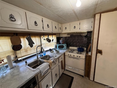 Kitchen with decorative backsplash, gas range gas stove, light countertops, a textured ceiling, and light tile patterned floors