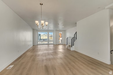 Unfurnished dining area featuring stairway, light wood-type flooring, and a chandelier