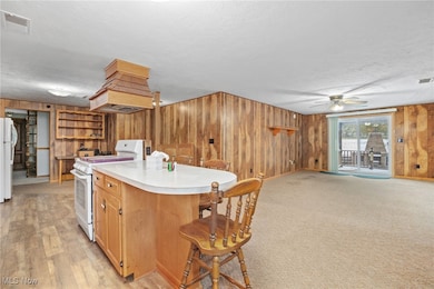 Kitchen with white appliances, premium range hood, light countertops, open floor plan, and wooden walls