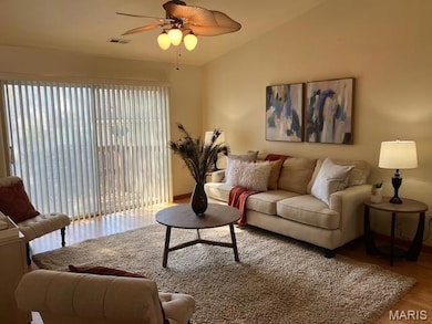 Living room featuring light wood-style flooring, a ceiling fan, and lofted ceiling