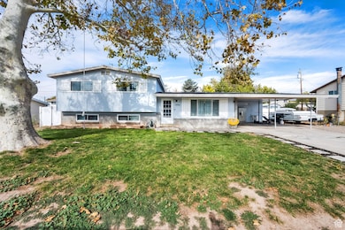 Split level home with a front yard, an attached carport, and concrete driveway