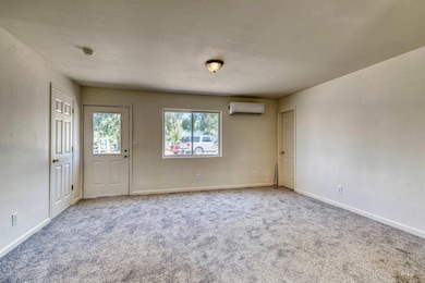 Carpeted spare room featuring a textured ceiling and a wall mounted AC