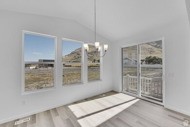 Unfurnished dining area with vaulted ceiling, a chandelier, wood finished floors, and a mountain view