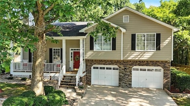 Split foyer home featuring brick siding, a porch, driveway, and a garage