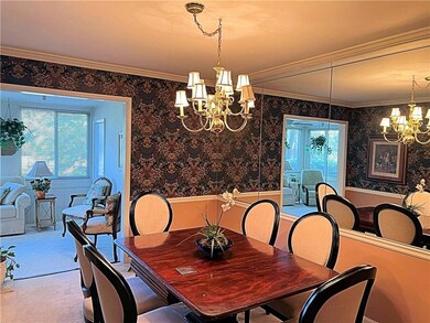 Dining room with a chandelier, crown molding, carpet flooring, wallpapered walls, and a wainscoted wall
