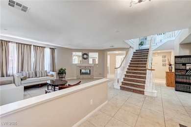 Living room with a tiled fireplace, stairway, ligh