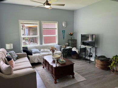 Living area with a ceiling fan, wood finished floors, and lofted ceiling