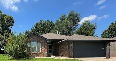 Single story home featuring brick siding, an attached garage, concrete driveway, a front yard, and roof with shingles