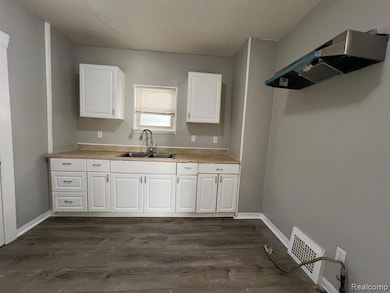 Kitchen featuring extractor fan, light countertops, white cabinets, and dark wood-type flooring