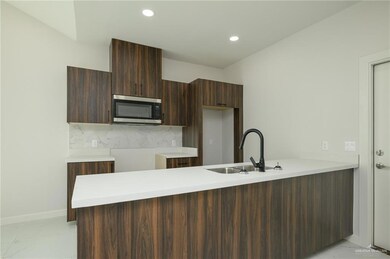Kitchen with stainless steel microwave, light marble finish floors, a sink, modern cabinets, and a peninsula