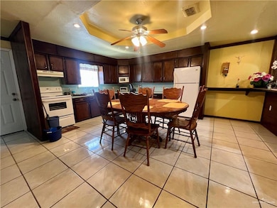Dining room featuring a tray ceiling, light tile patterned floors, ceiling fan, recessed lighting, and a textured ceiling