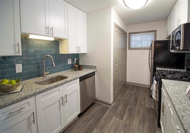 Kitchen with white cabinetry, stainless steel appliances, sink, and dark hardwood / wood-style flooring