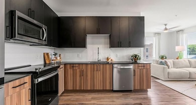 Kitchen with decorative backsplash, appliances with stainless steel finishes, light wood-type flooring, ceiling fan, and sink