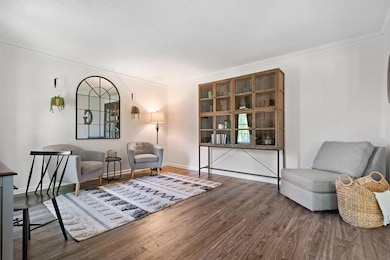 Living area with wood finished floors and ornamental molding