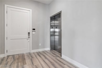 Entryway featuring elevator, baseboards, and light