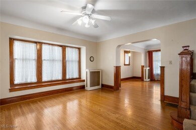Empty room with arched walkways, light wood-style floors, and ceiling fan