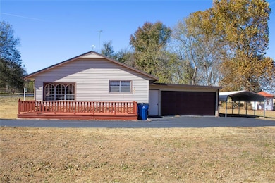 View of side of home featuring a garage, a lawn, and a wooden deck