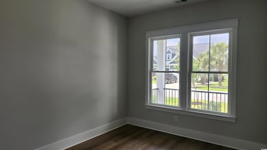 Empty room with healthy amount of natural light, baseboards, and dark wood-style flooring