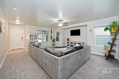Living area with light colored carpet, plenty of natural light, and a ceiling fan