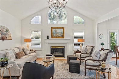 Living area with wood finished floors, high vaulted ceiling, a glass covered fireplace, and a chandelier