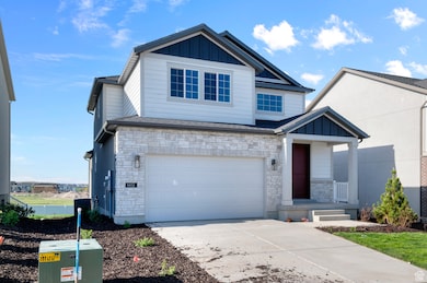 View of front facade featuring stone siding, board and batten siding, an attached garage, concrete driveway, and covered porch