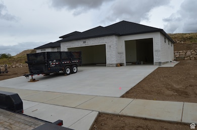 View of front facade featuring concrete driveway, a garage, and a shingled roof