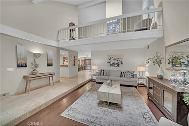 Large Formal Living Room with Loft Balcony Above, Soaring Cathedral Ceiling, Plank-Style Wood Laminate Flooring and Raised Center Travertine Foyer/Entry