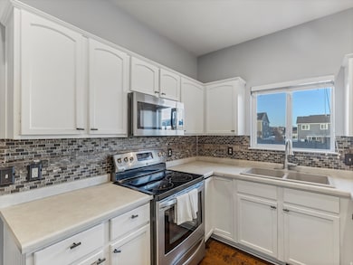 Kitchen featuring stainless steel appliances, white cabinets, and backsplash