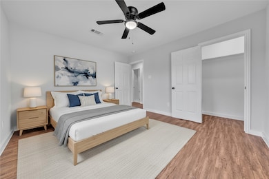 Bedroom with a ceiling fan, a spacious closet, and wood finished floors