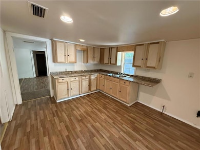 Kitchen with light brown cabinetry, dark wood-type flooring, dark countertops, and recessed lighting