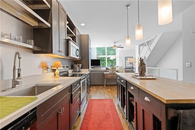 Kitchen with open shelves, stainless steel appliances, ceiling fan, pendant lighting, and wood finished floors
