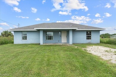 View of front of property featuring stucco siding, a shingled roof, a patio, and a front lawn