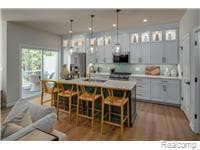 Kitchen featuring a kitchen bar, a center island with sink, light countertops, pendant lighting, and dark wood-style flooring
