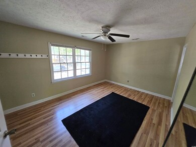 Unfurnished room featuring baseboards, a ceiling fan, wood finished floors, and a textured ceiling