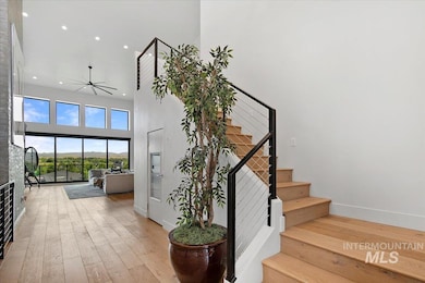 Stairs featuring a towering ceiling, hardwood / wood-style floors, a ceiling fan, and recessed lighting
