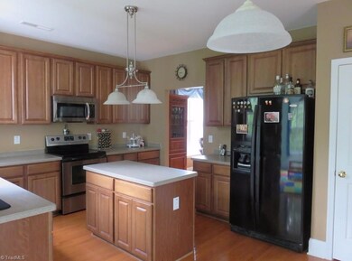 A glorious kitchen awaits you with solid surface counter tops  below tall raised panel maple cabinets. A pantry is on the right .