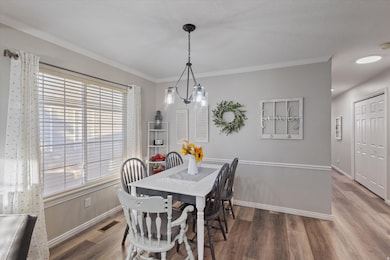 Dining space with ornamental molding and wood finished floors