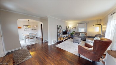 Living room with dark hardwood / wood-style flooring, an inviting chandelier, and ornamental molding
