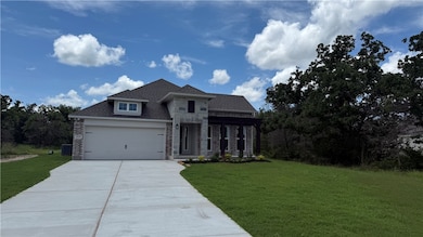 View of front facade with stone siding, driveway,