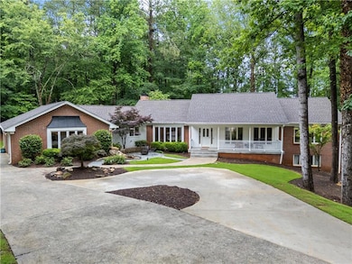 Ranch-style house featuring covered porch, driveway, brick siding, a chimney, and a shingled roof