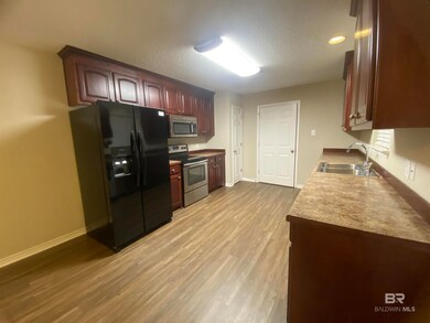 Kitchen with light wood-type flooring, appliances with stainless steel finishes, a textured ceiling, and sink