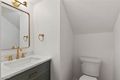 Half bath featuring vanity and vaulted ceiling
