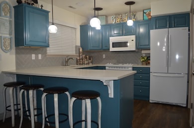 Kitchen featuring blue cabinetry, white appliances, and backsplash