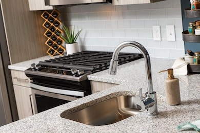 Kitchen view of tasteful backsplash, light stone countertops, and freestanding refrigerator